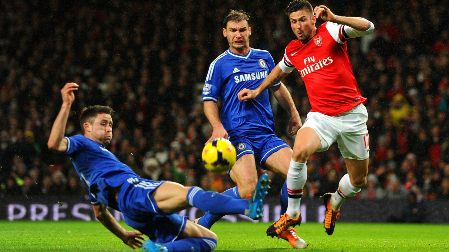 Gary Cahill of Chelsea tackles Olivier Giroud of Arsenal in a wet and windy match in north London