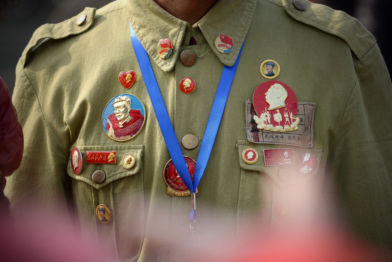 A man displays badges of Mao Zedong.