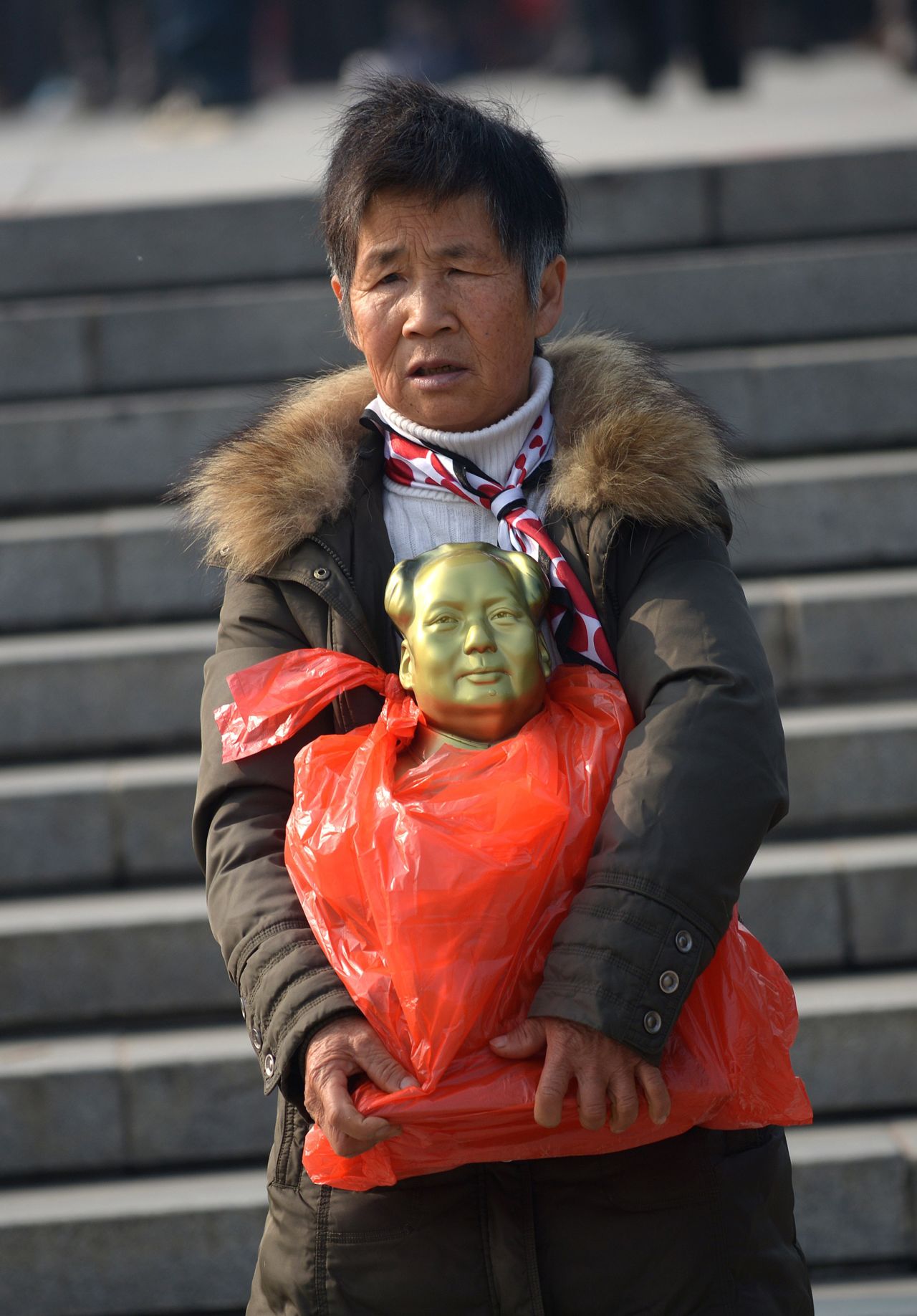 An elderly woman holds a bronze statue of China's former leader Mao Zedong as she makes her way in China's central province of Hunan on December 24, joining others in celebrating Mao's 120th anniversary this week.