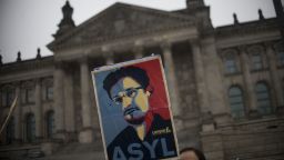 Campact activists hold up a portrait of US whistleblower Edward Snowden in front of the Reichstag building housing the Bundestag (lower house of parliament) in Berlin on November 18, 2013. German MPs were to hold a session at the Bundestag, focusing on the spying methods of the US National Security Agency (NSA) and its impact on Germany and transatlantic relationship. Snowden, former NSA contractor, had said before he was ready to help Germany following revelations, based on documents he provided, that have included the tapping of German Chancellor Angela Merkel's phone