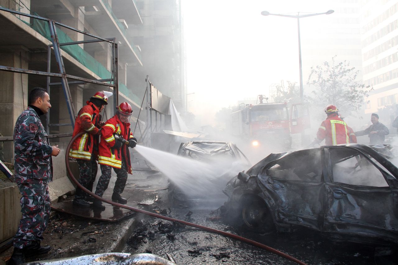 Firefighters douse a burning car after the explosion in central Beirut.