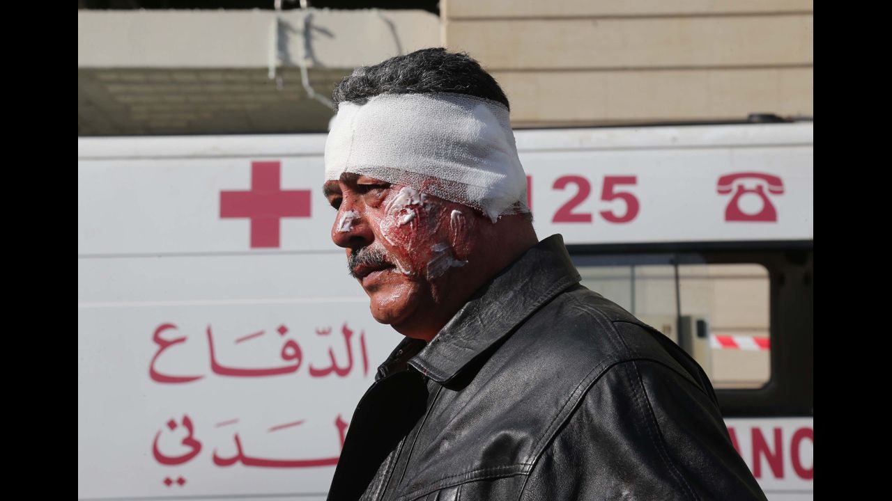 A wounded man walks past a Lebanese civil defense ambulance near the scene.