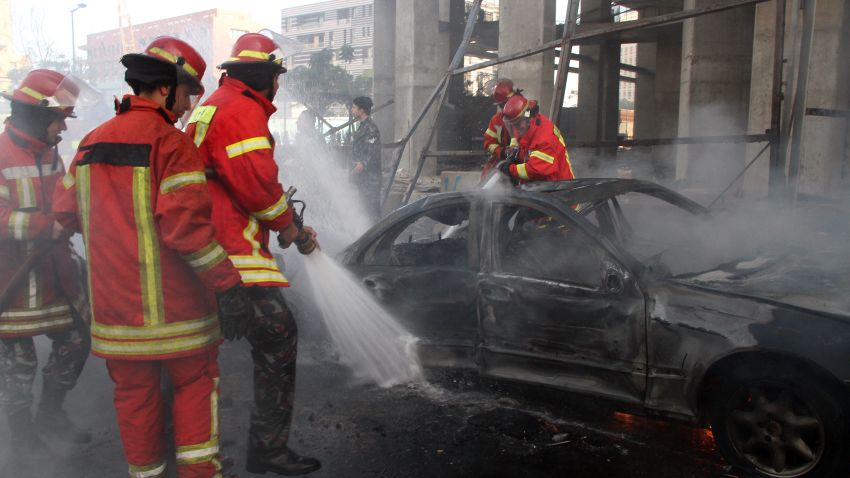 Firemen douse a burning car following a huge blast that rocked central Beirut on December 27, 2013