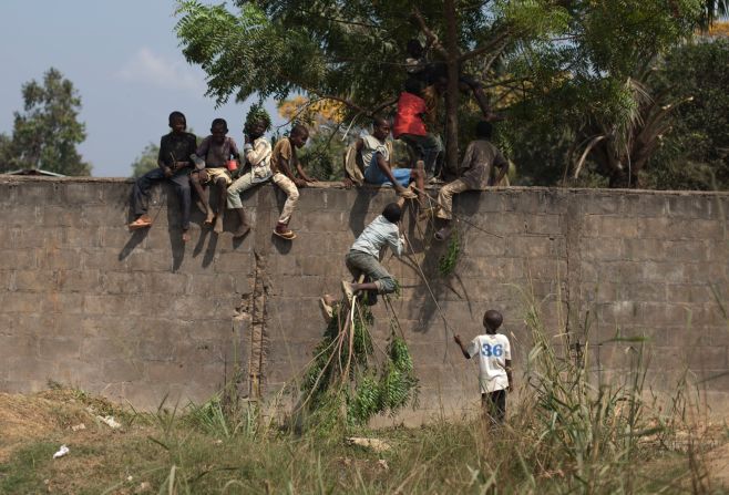 Displaced young people use a tree branch to climb a wall in Bangui on Saturday, December 28.