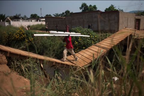 A man carries beams stripped from a Bangui house, back left, which is said to have belonged to a Seleka officer who had been attacking the surrounding Christian population.