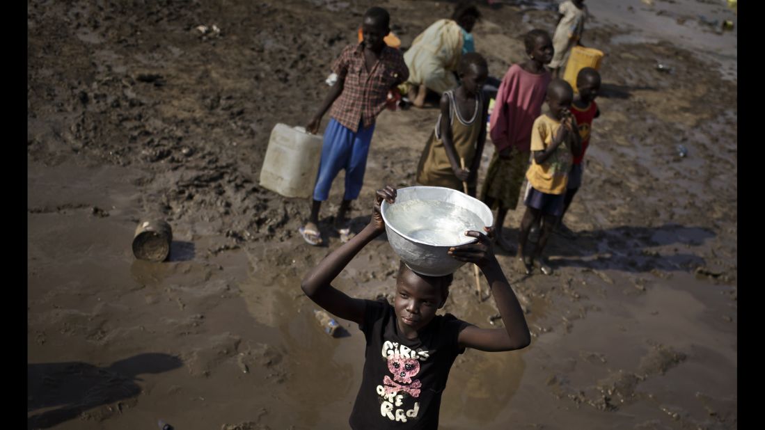A girl carries a bowl of water after filling it from a truck at the U.N. compound in Juba on December 29.