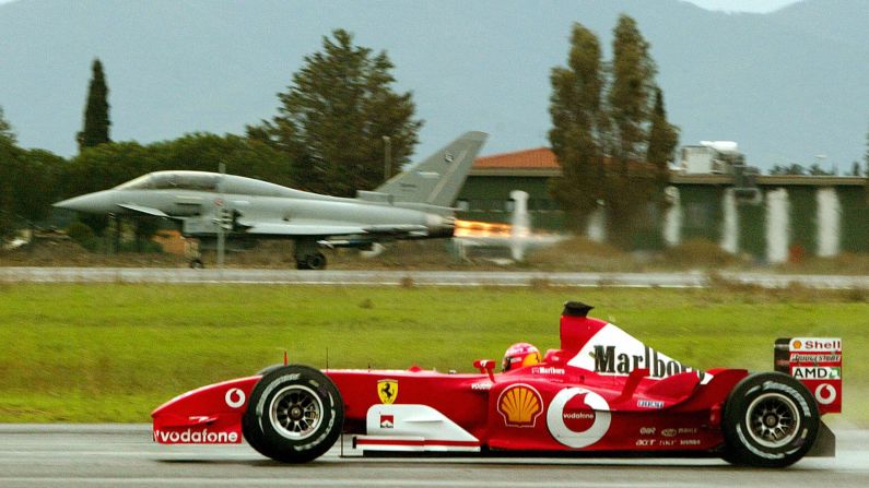 Schumacher conduce su Ferrari frente a un Eurofighter en la pista de un aeropuerto militar en Grosseto, Italia, en 2003.