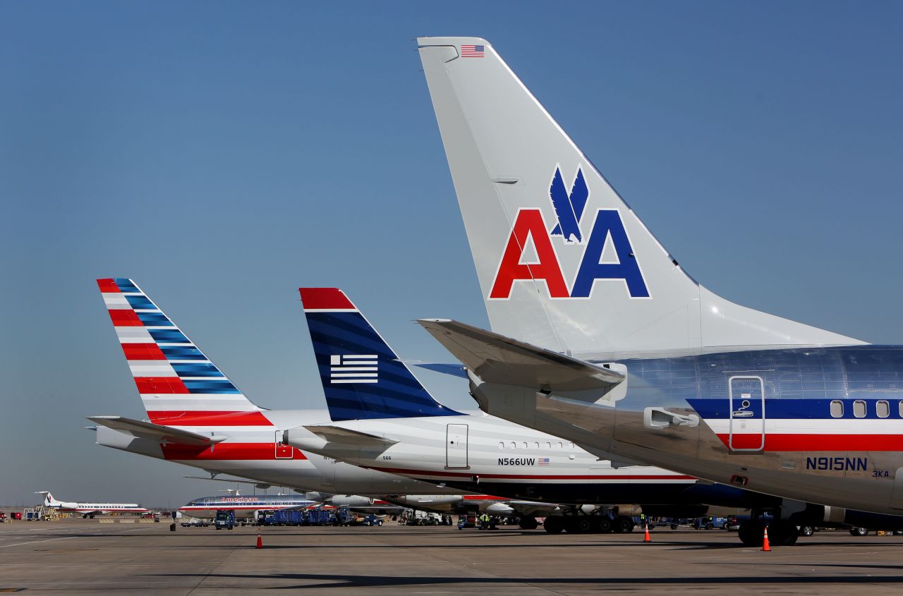 A US Airways airplane, center, is flanked by American Airlines jets at Dallas/Fort Worth International Airport on February 14, 2013. The two airlines merged in December 2013 to create the world's largest airline.