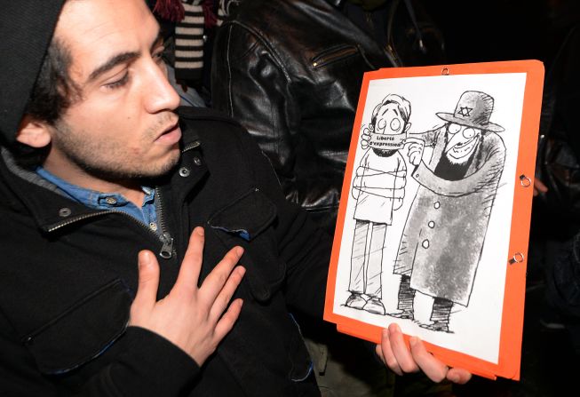 Supporters of Dieudonne argue that the issue of "freedom of speech" in France is at stake after Valls called for the comic's performances to be banned. Here a man poses with one of his drawings showing a Jewish character covering the mouth of another character with a gag reading "freedom of speech."