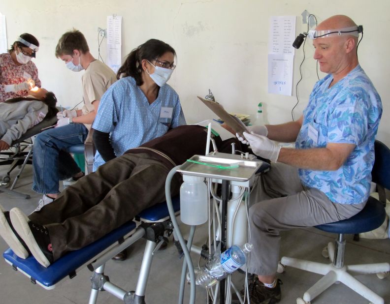 CNN reporter Moni Basu, center, helps pediatric dentist Raymond Broussard, right, at the clinic. The hours were long, but satisfying, she said.