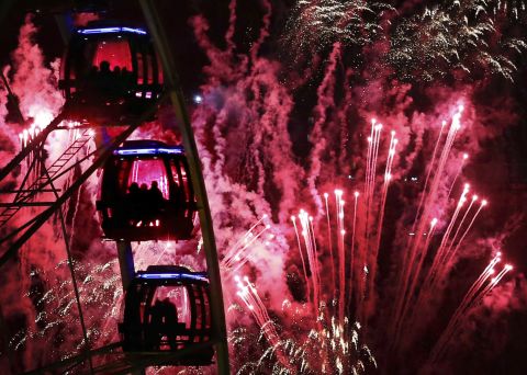 People ride a Ferris wheel as fireworks illuminate the sky during New Year's celebrations in Edinburgh, Scotland.