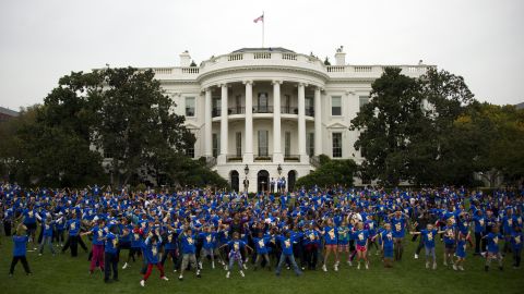 First Lady Michelle Obama is surrounded by school children doing jumping jacks during a 'Let's Move!' event, October 11, 2011.