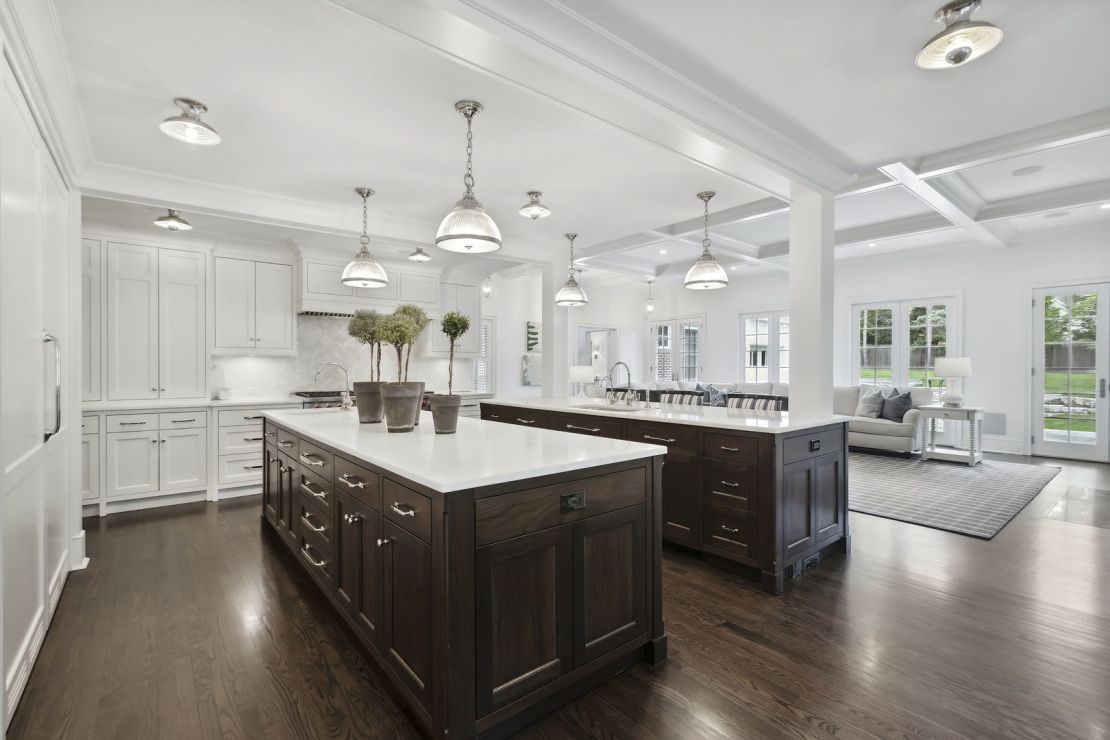 The home is fitted with "a magazine-worthy gourmet kitchen" featuring double islands, bespoke white cabinetry, and an eight-burner Wolf range.