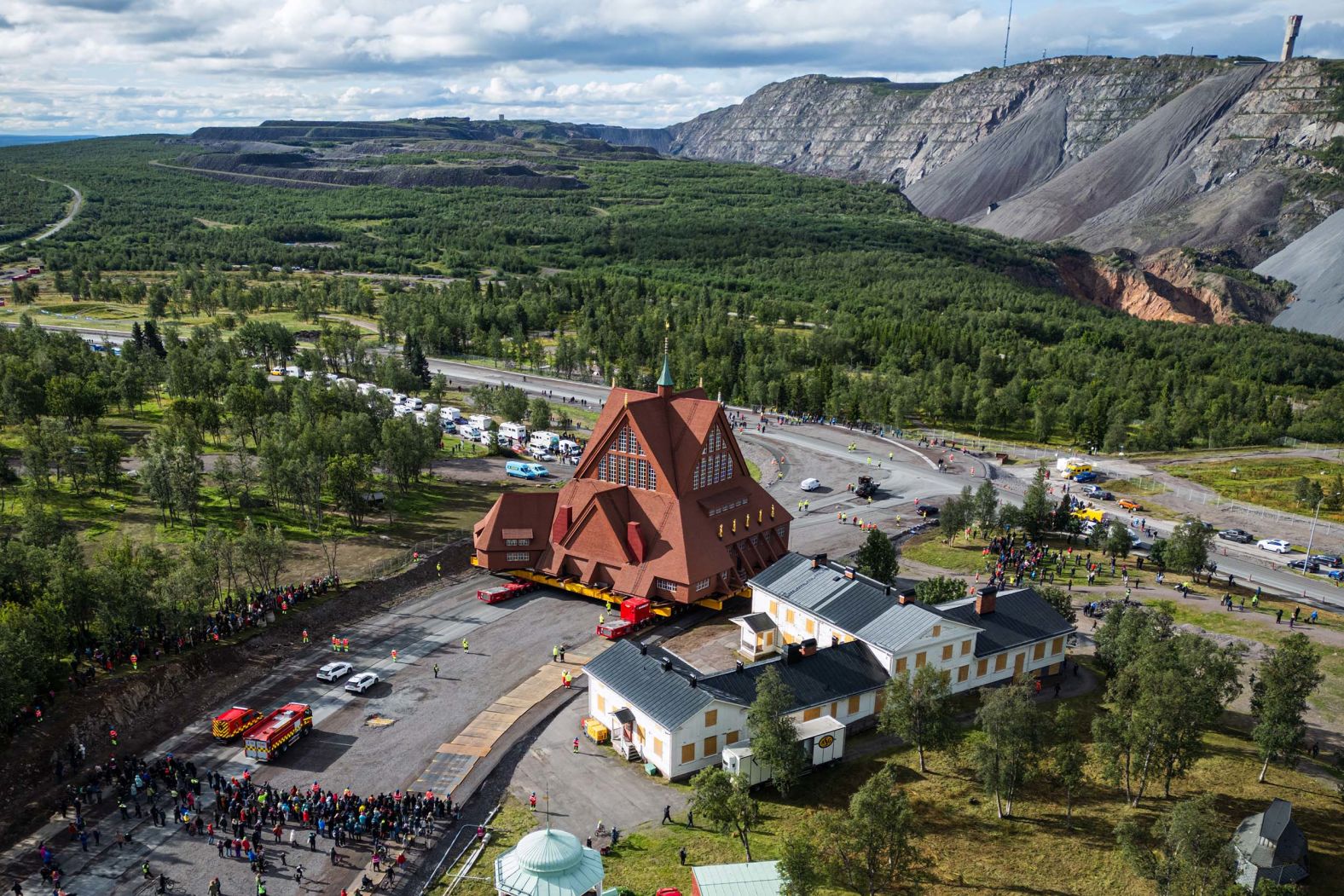 People gather to watch as the wooden Kiruna Church is moved in Kiruna, Sweden, on Tuesday, August 19. The church was being relocated due to the expansion of an iron-ore mine.
