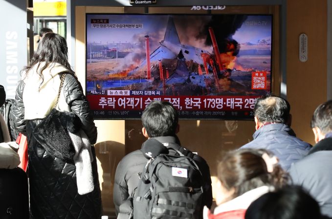 People watch a news broadcast on the plane crash at Seoul Station in Seoul, South Korea.