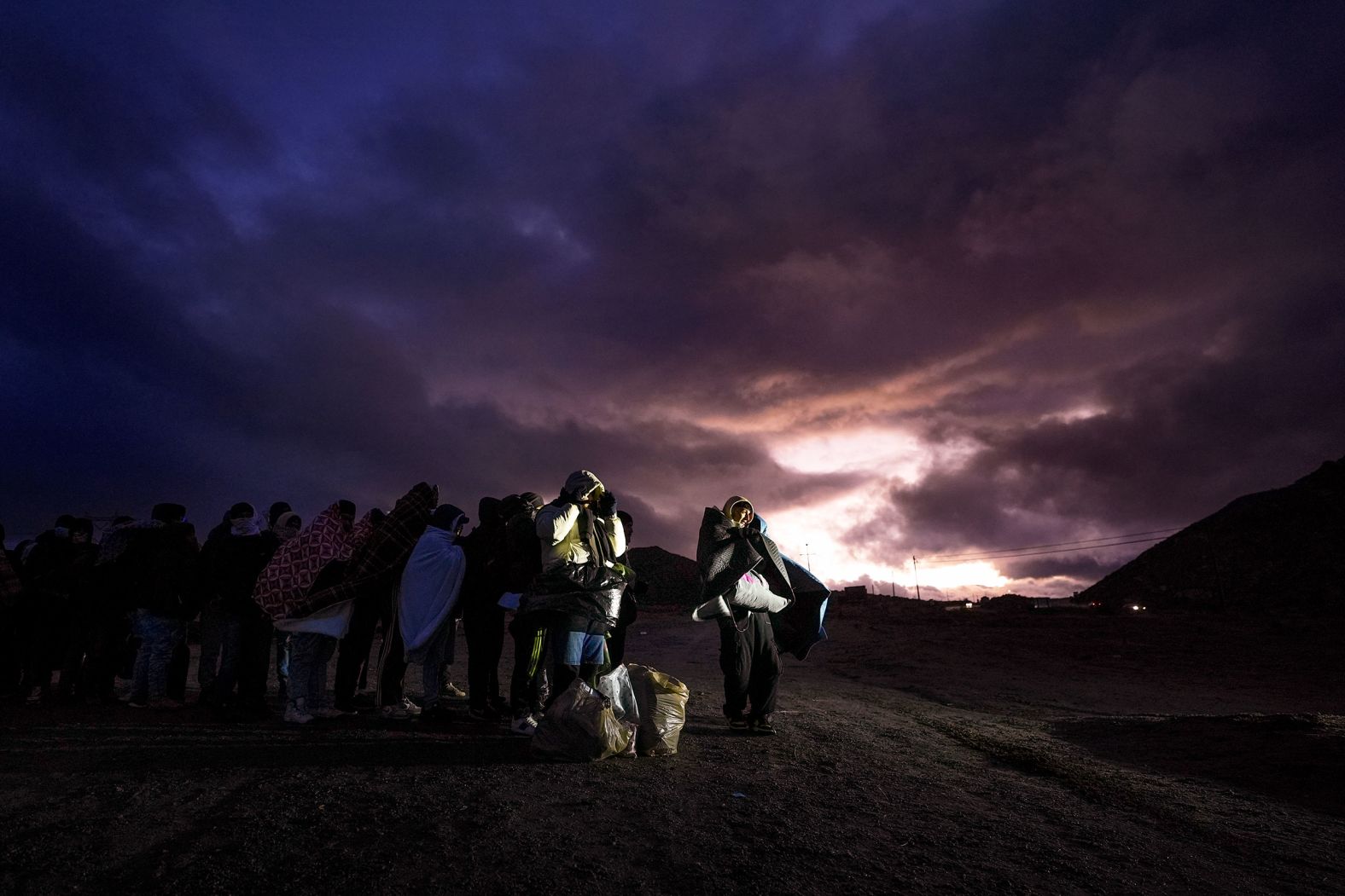 Migrants, wrapped in blankets to ward off the heavy wind and rain, line up to be processed by the US Border Patrol after they illegally crossed into a mountainous area near Jacumba Hot Springs, California, on Friday, February 2.
