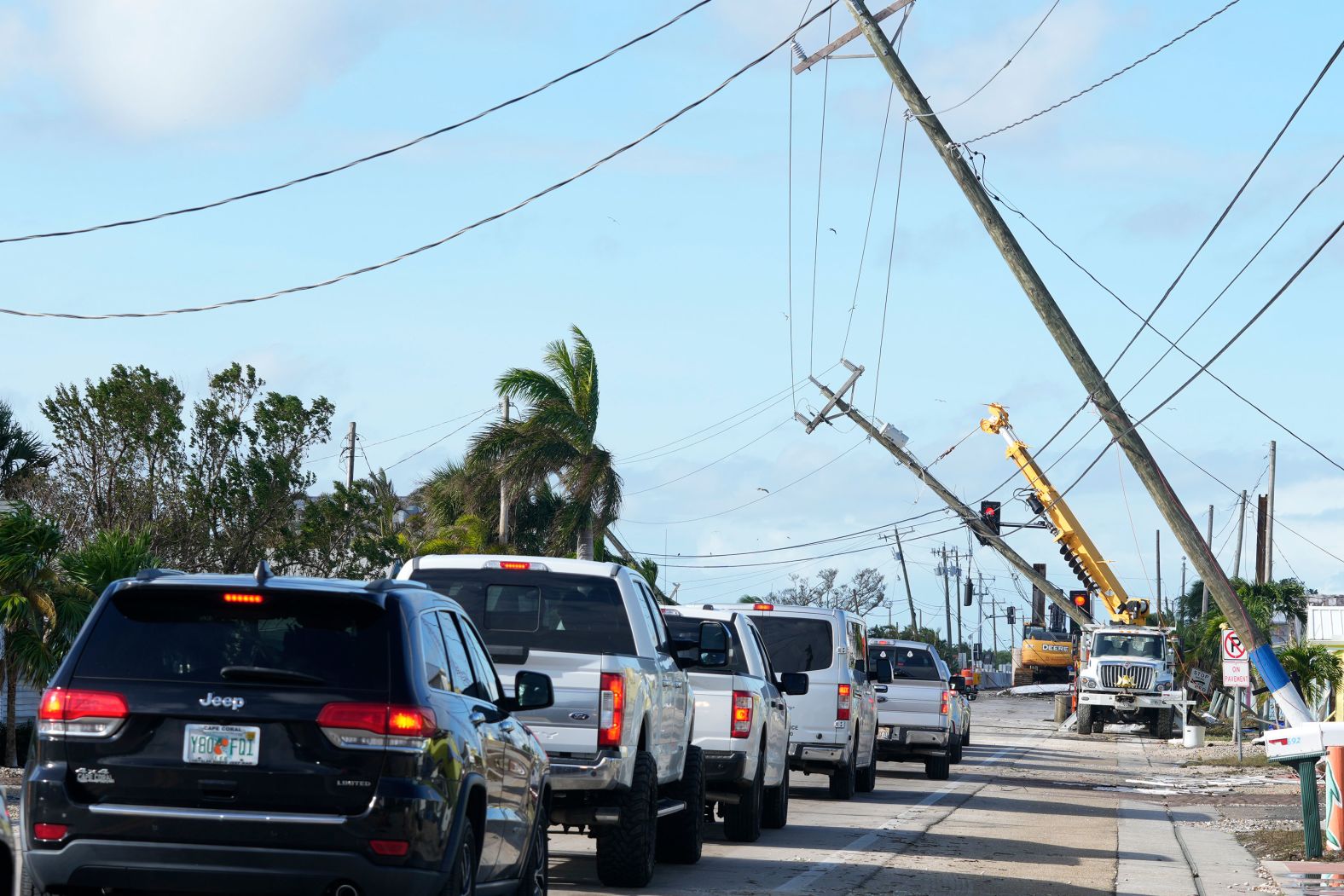 Cars move slowly through Matlacha, Florida, on Thursday after Hurricane Milton damaged power lines.