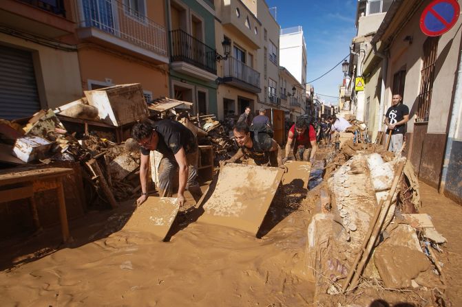 People try to clear mud from a street in Paiporta on Friday.