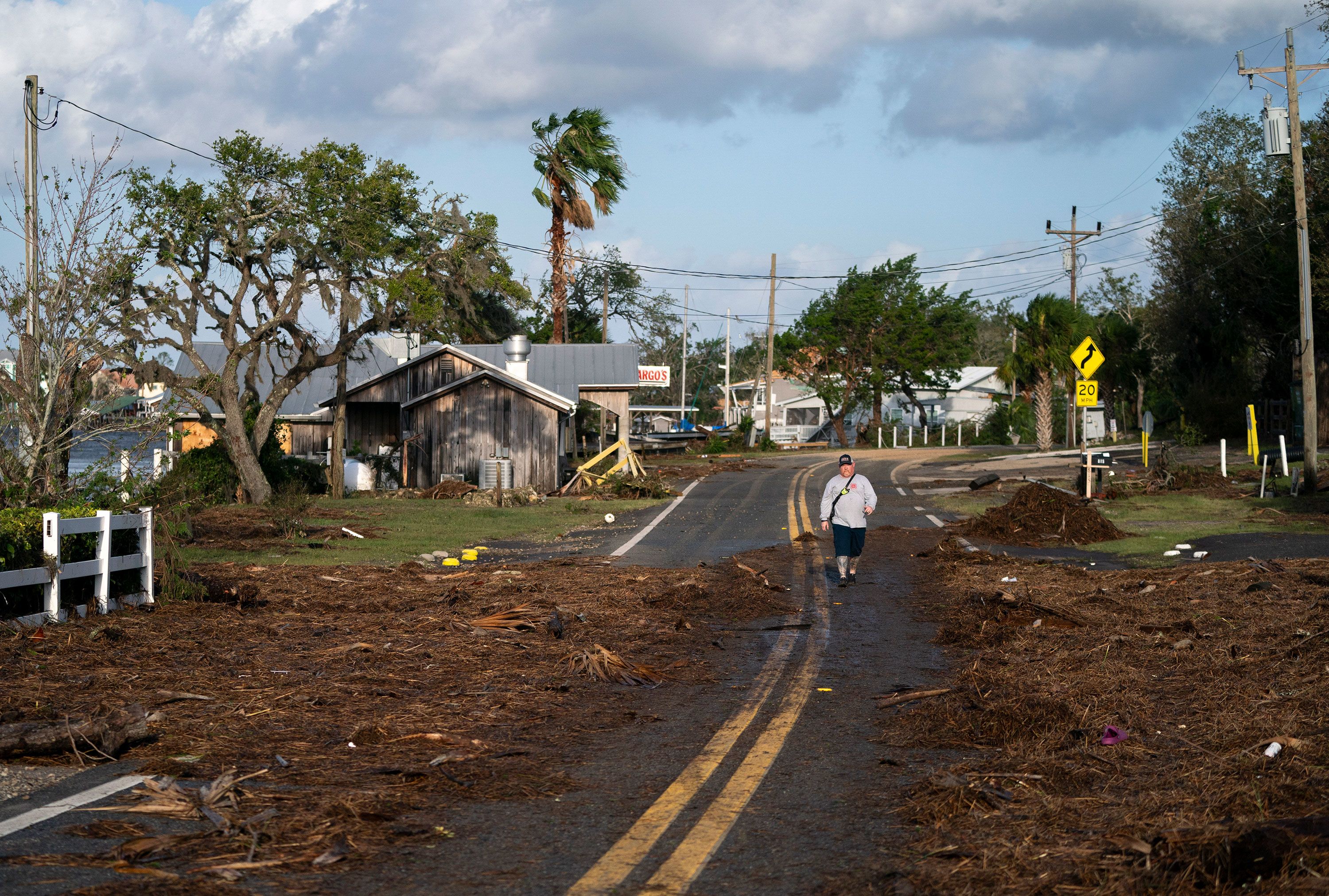 A fireman walking through a street in Steinhatchee, Florida, amidst storm debris.