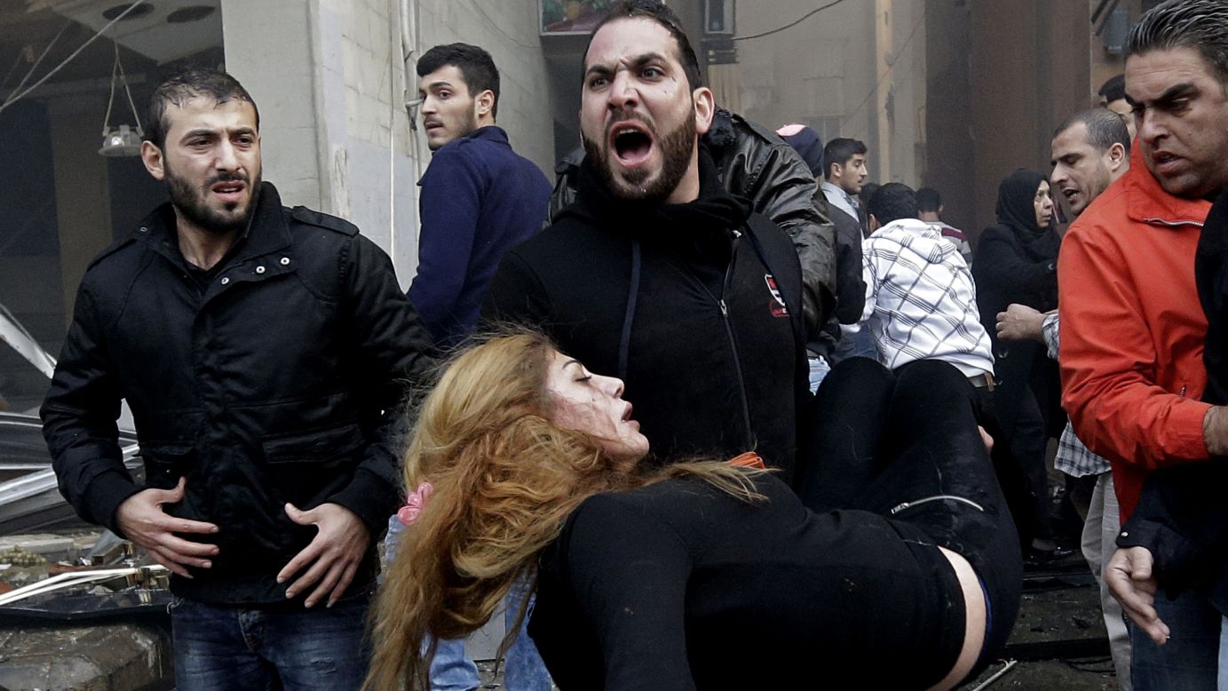 A man carries an injured woman away from the site of a car bomb explosion in Beirut, Lebanon, on Thursday, January 2. The bomb went off in a residential neighborhood of southern Beirut.