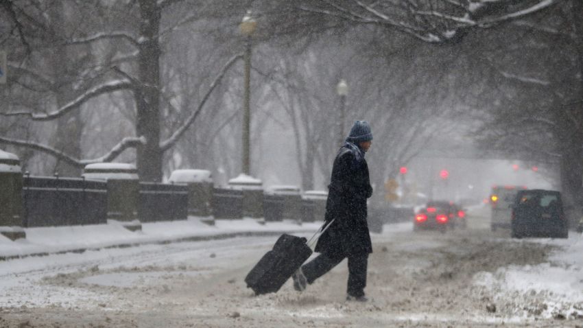 A man drags a suitcase on a snowy street in downtown Boston, on Thursday, January 2. Up to 14 inches of snow is forecast for the Boston area.