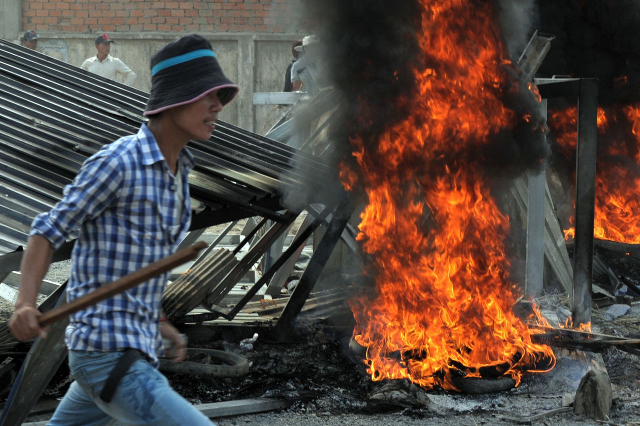 A  man armed with a wooden stick rallies during a protest in front of a garment factory in Phnom Penh on January 3.