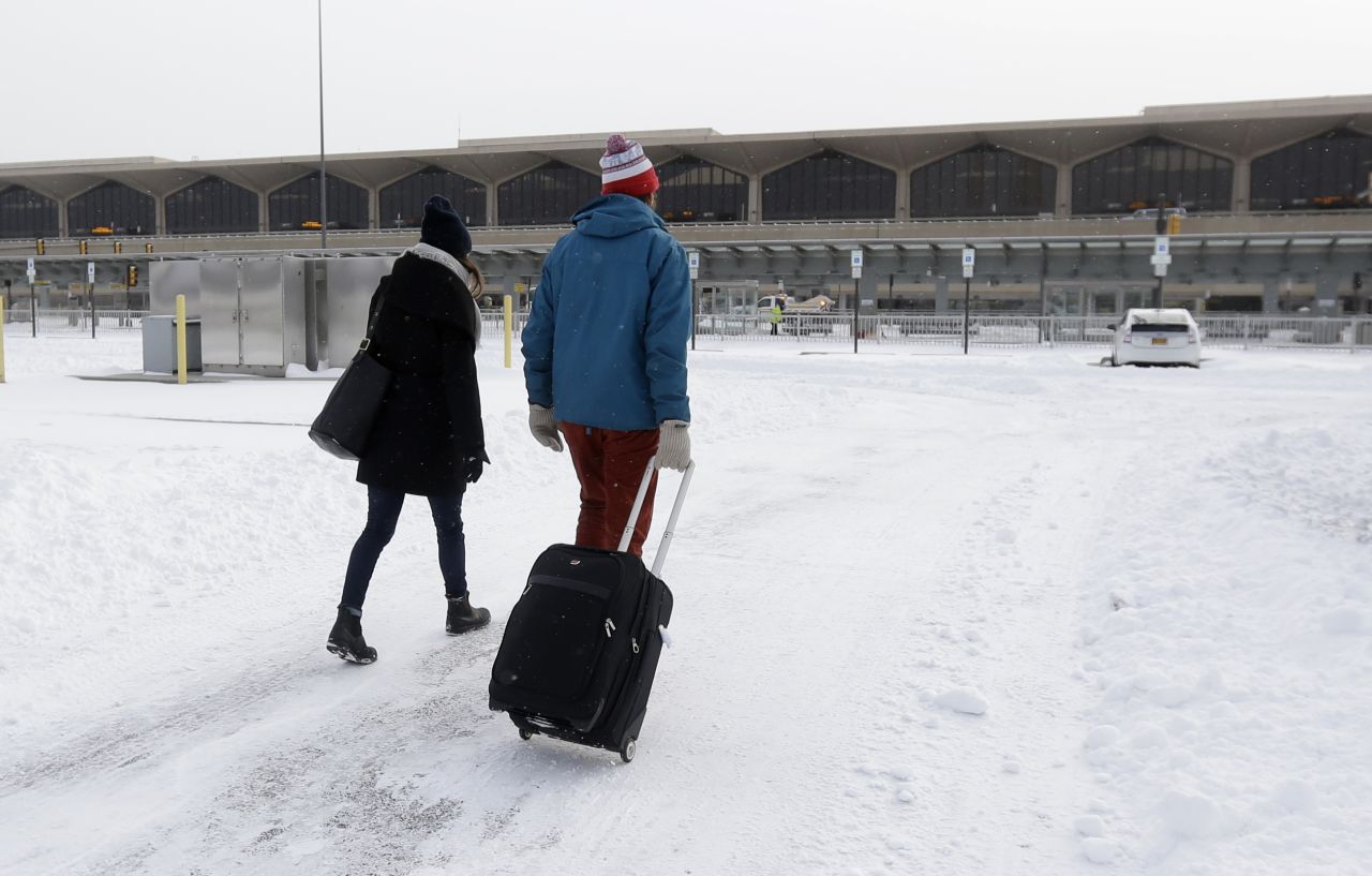A couple walks across a snow-covered parking lot January 3 at Newark Liberty International Airport. 