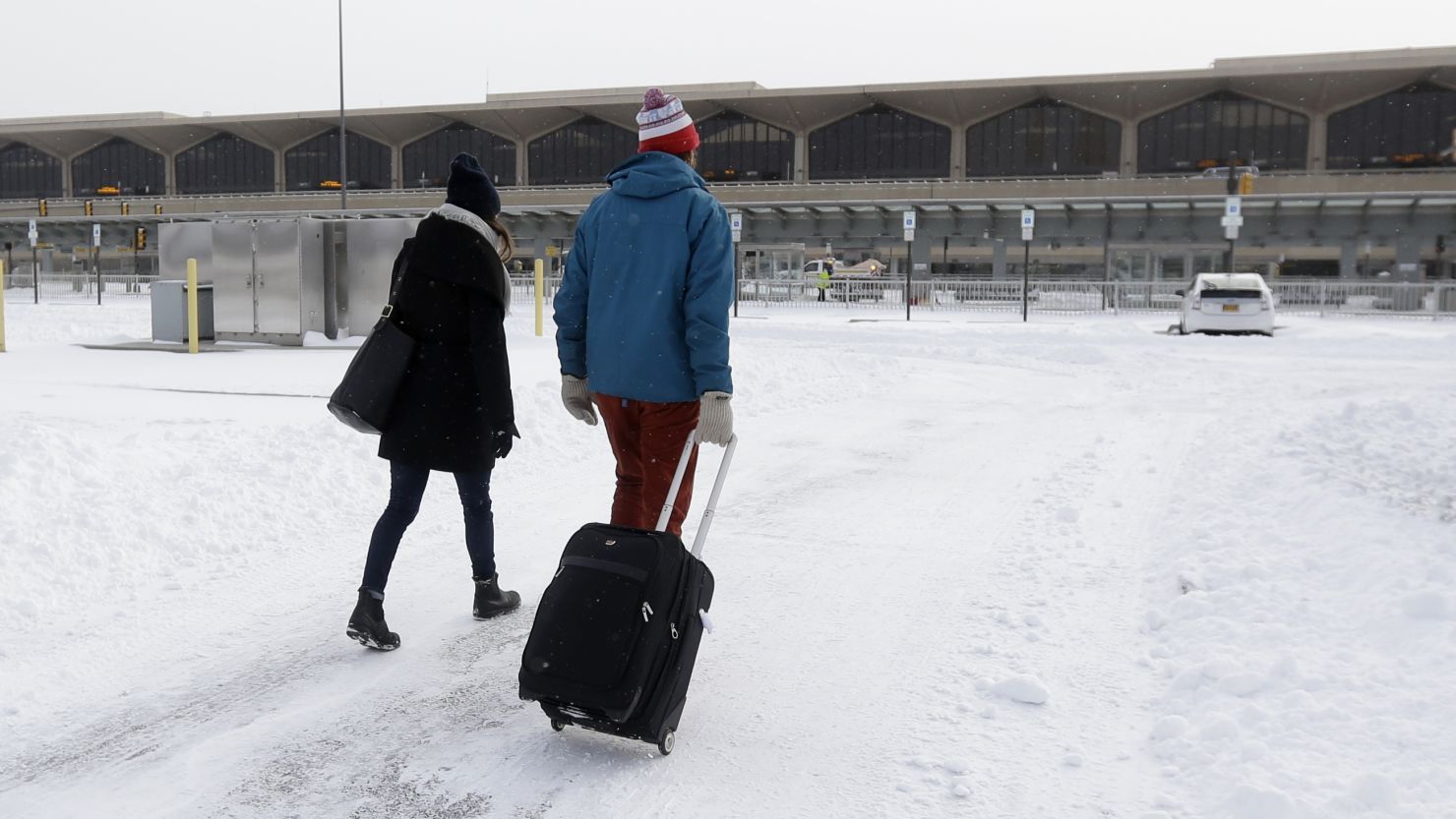 Travelers walk across a snow-covered parking lot at Newark Liberty International Airport on Friday.