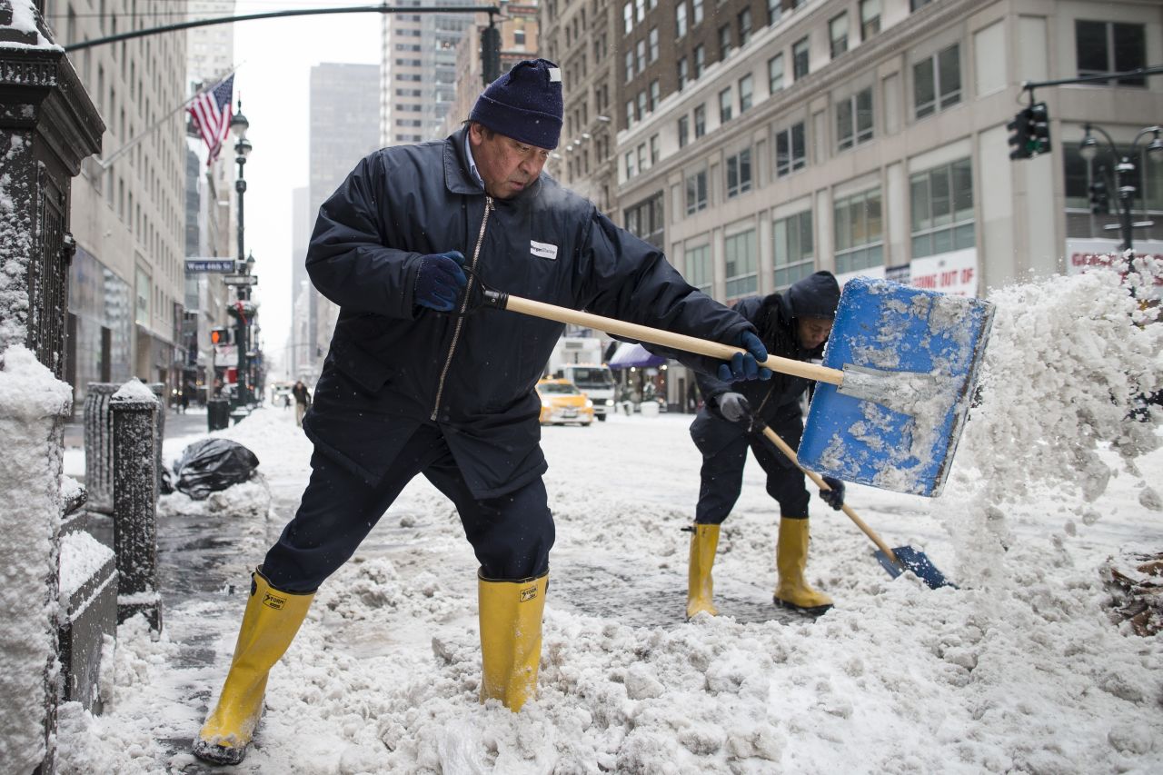 Workers clear snow off sidewalks on New York City's Fifth Avenue on January 3.