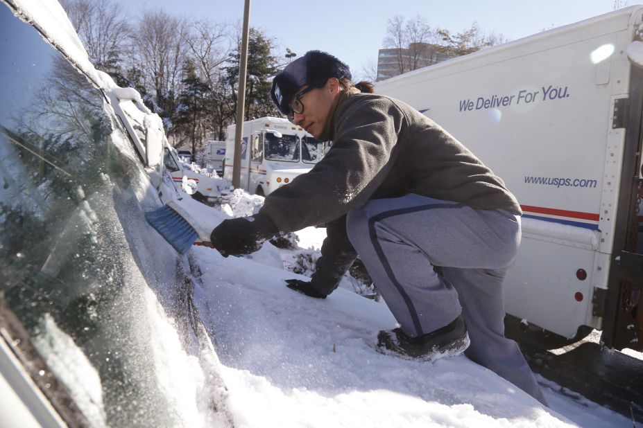 Postal worker Danny Kim clears snow and ice off the hood of his delivery truck January 3 in Bethesda, Maryland.