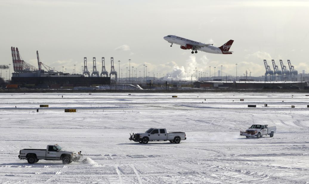 A plane takes off January 3 as trucks plow snow at Newark Liberty International Airport in Newark, New Jersey.