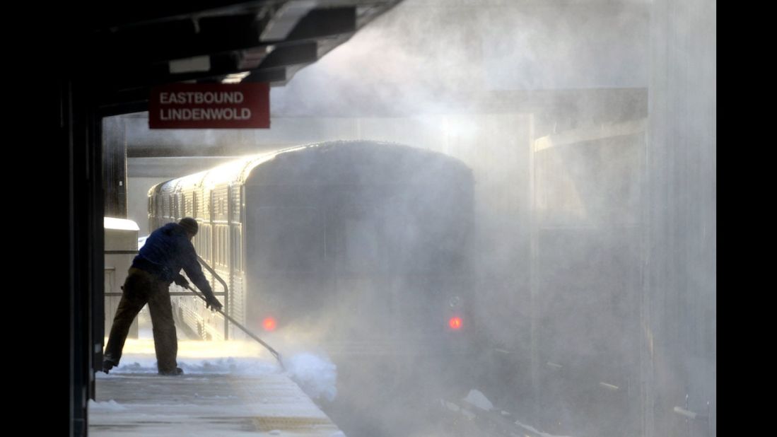 Blowing snow swirls as a worker shovels a platform at a Haddonfield, New Jersey, train station on January 3.