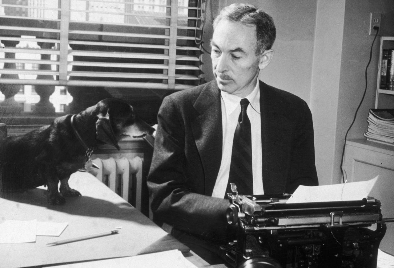 Writer E.B. White looks at his pet dachshund, Minnie, while typing in his office at The New Yorker magazine circa 1948.