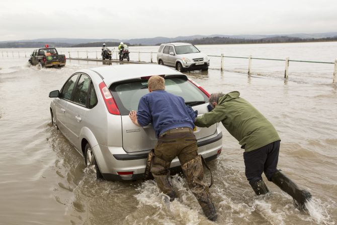 People push a car toward higher ground in Storth, England, on January 4. 