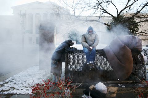 Four homeless men warm themselves on a steam grate by the Federal Trade Commission Building, blocks from the U.S. Capitol in Washington, as frigid temperatures grip the nation's capital on Saturday, January 4.