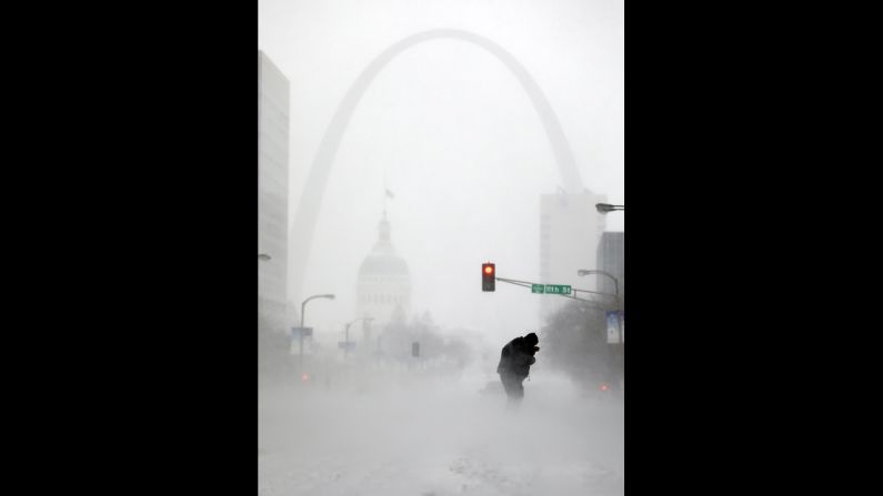 With the Gateway Arch in the distance, a person struggles to cross the street during a snowstorm January 5 in downtown St. Louis.