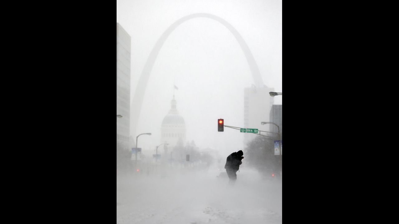 With the Gateway Arch in the distance, a person struggles to cross the street during a snowstorm January 5 in downtown St. Louis.