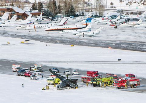Firetrucks and ambulances surround the crash site. The airport tarmac is often filled with private planes owned or chartered by people who own vacation homes in the mountain resort community.