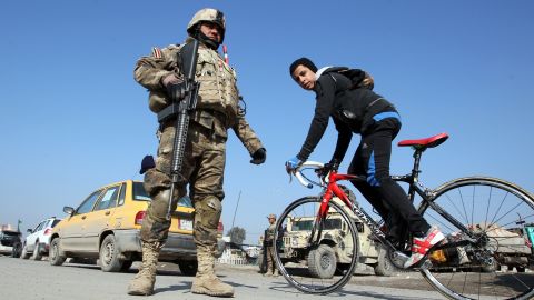 A boy cycles past Iraqi soldiers monitoring a checkpoint east of Baghdad on January 6, 2014.