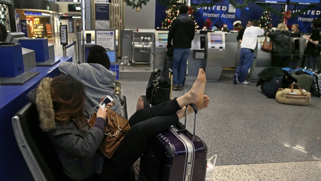 A woman props up her feet on her luggage January 6 after her flight home was canceled at Logan International Airport in Boston.