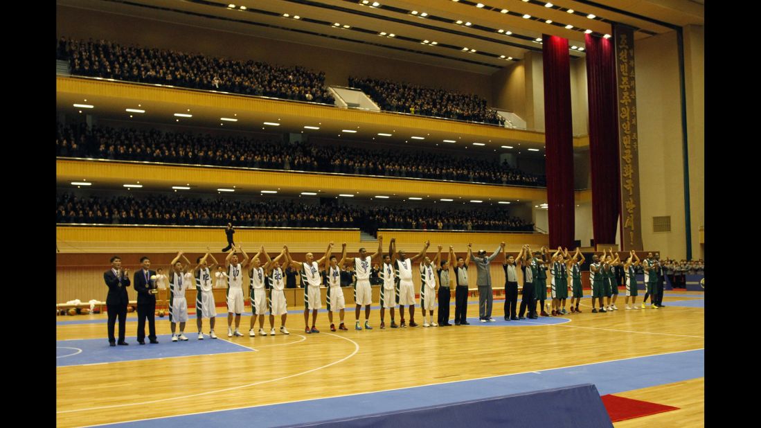 U.S. and North Korean basketball players raise their hands to the crowd after the game.
