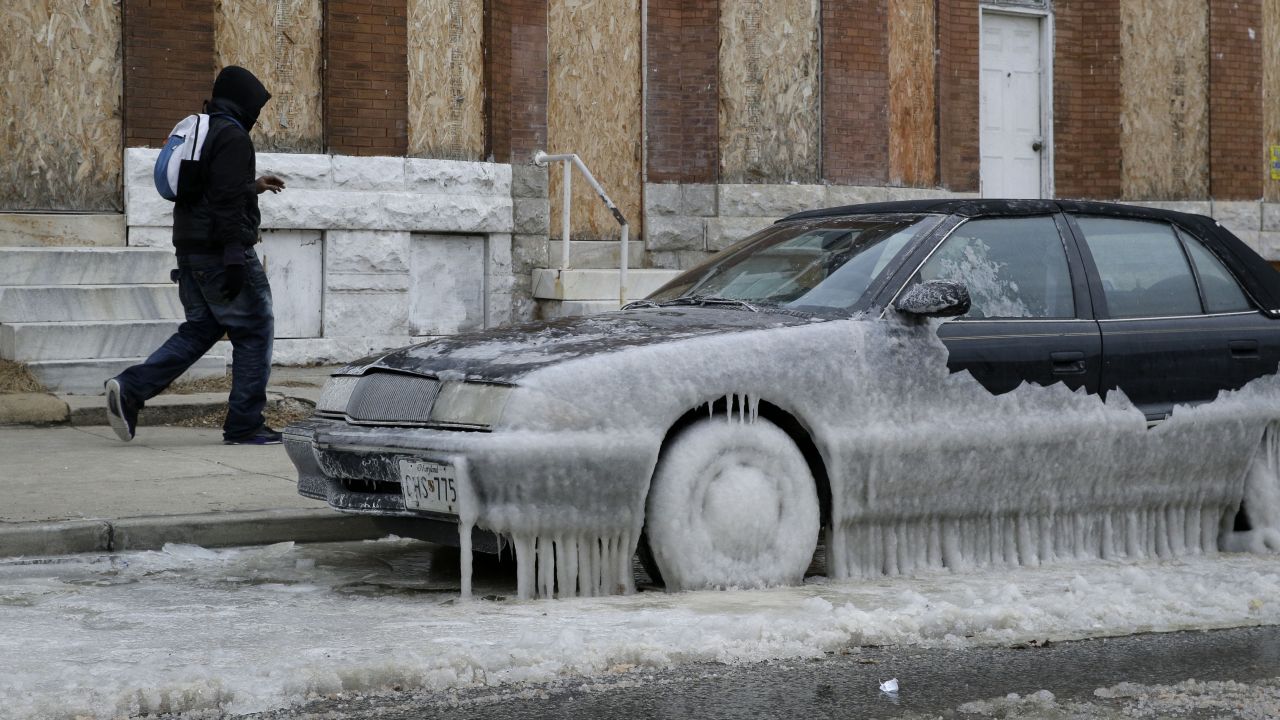 A man walks past a car in Baltimore that is partially covered in ice January 8.