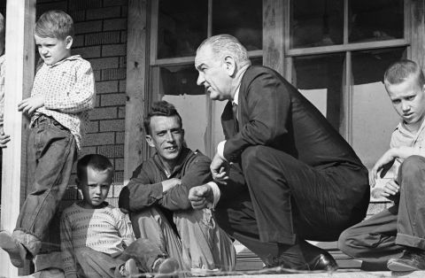 U.S. President Lyndon B. Johnson visits a family in Inez, Kentucky, during a tour of poverty-stricken areas of the country in April 1964. Earlier that year, Johnson declared a "war on poverty" in his State of the Union address. He then worked with Congress to pass more than 200 pieces of legislation, which included early education programs and social safety nets such as Medicare and Medicaid.