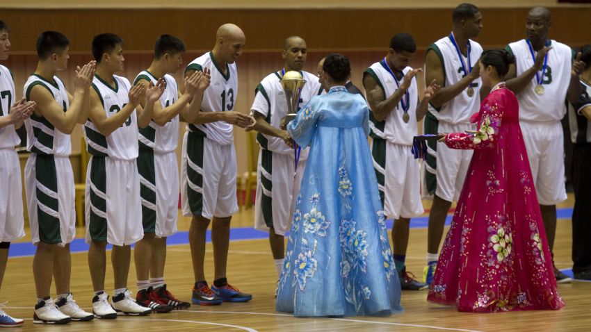 Doug Christie is handed a trophy as North Korean players applaud at the end of the game.
