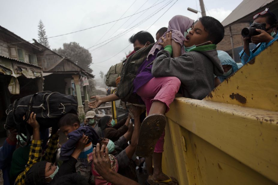 A man helps children onto a truck as residents are evacuated.
