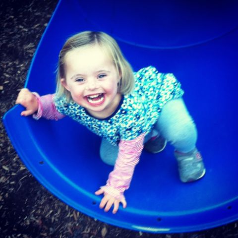 Ellie clambers off a playground slide at 4.