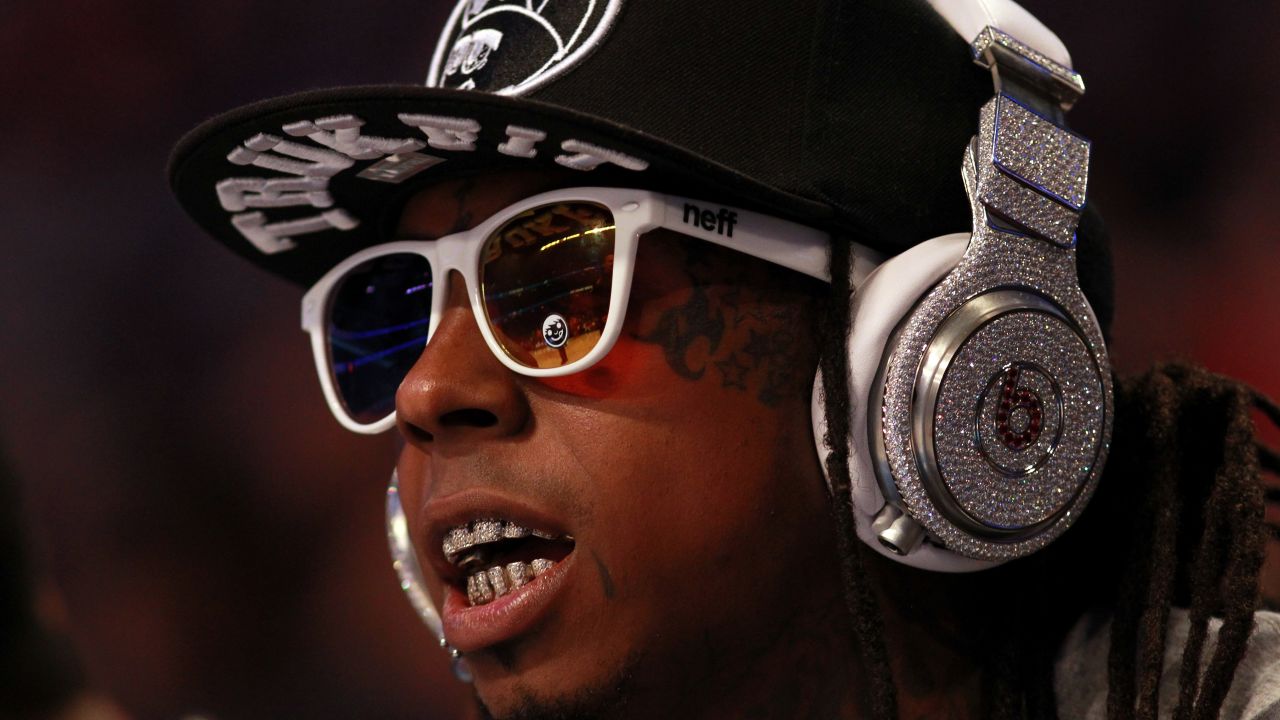 Hip-hop artist Lil' Wayne, wearing diamond-studded Beats headphones, sits courtside during the 2012 NBA All-Star Game.