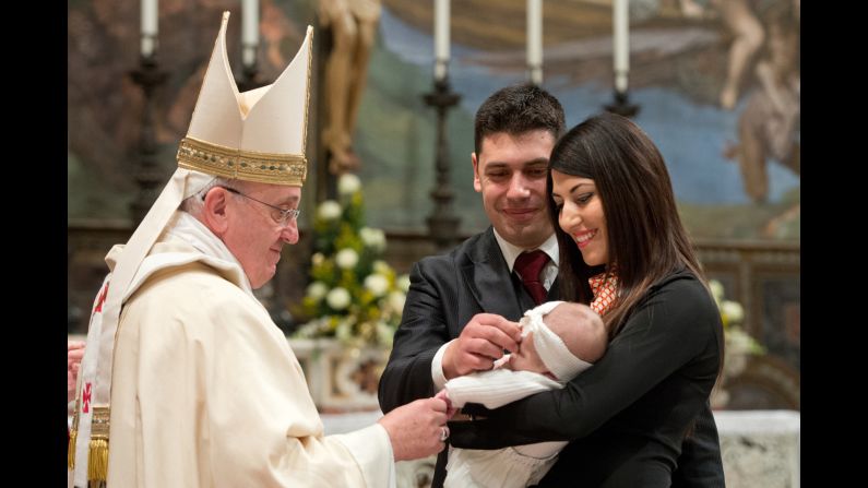 The Pope blesses a baby during the baptism ceremony.