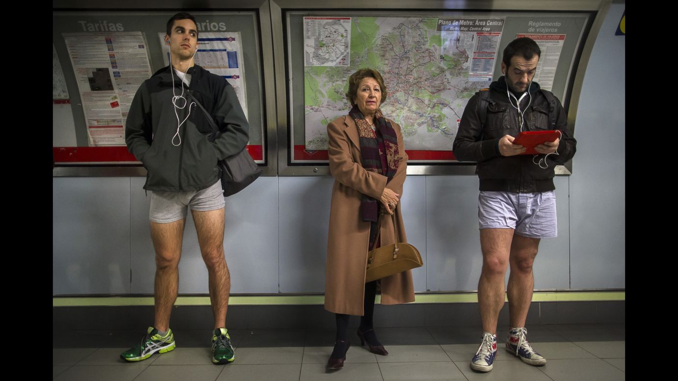 A woman stands between two pantsless passengers in Madrid.