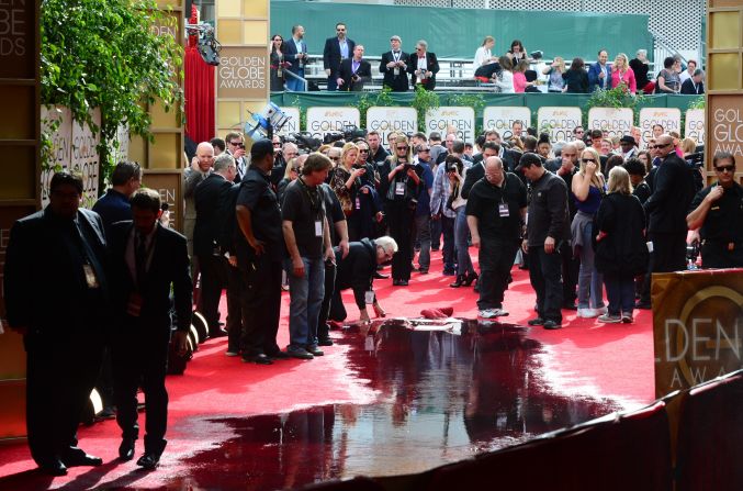 Staff clean up after a sprinkler malfunction dumped water on the red carpet before the start of the event.